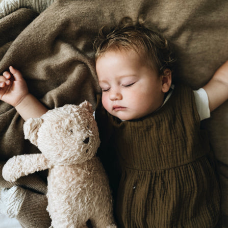 bébé endormi avec la peluche Moonie bear contre lui.