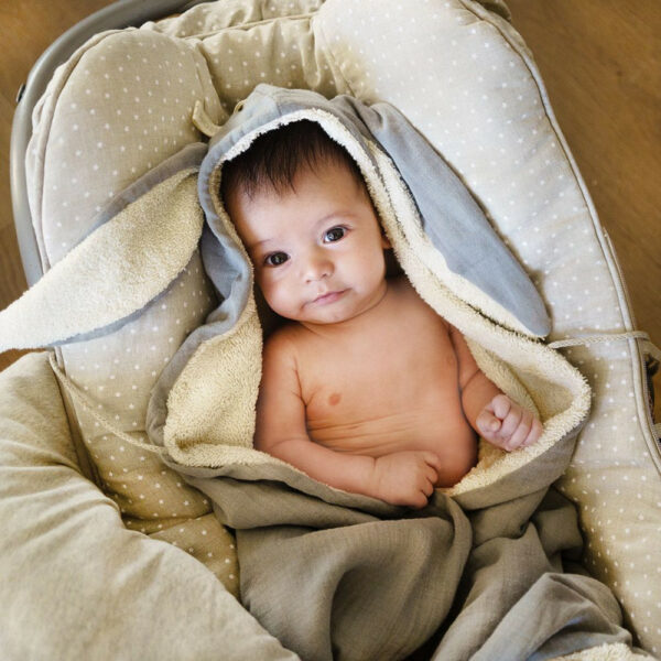 image representant un bebe dans une cape de bain avec des oreilles de lapin.